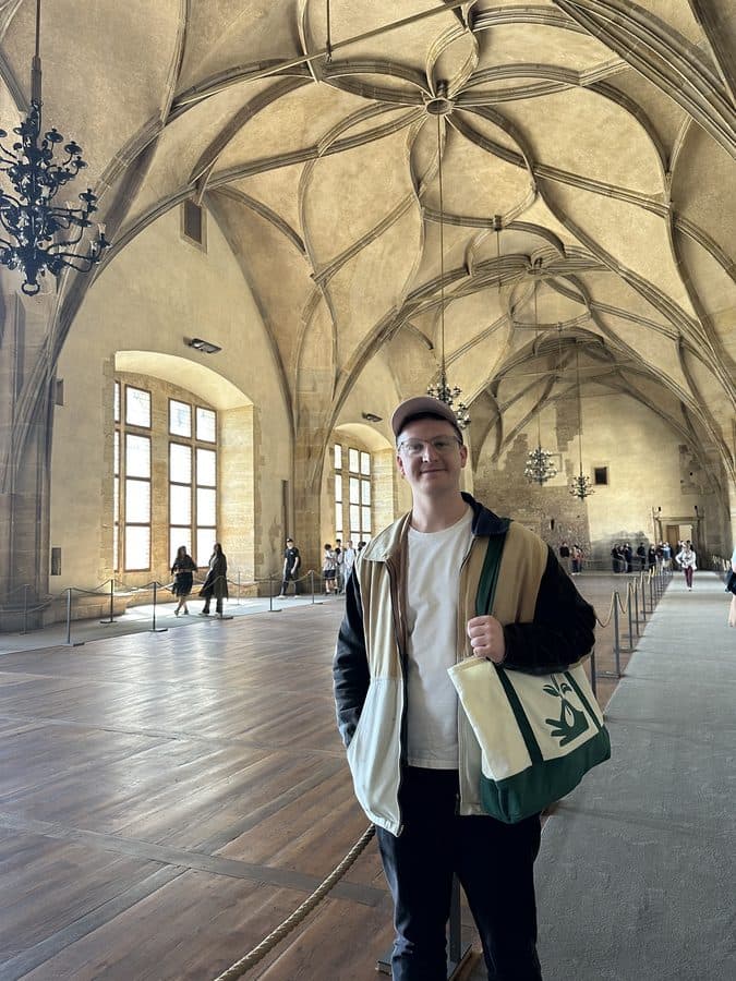 Aidan standing under the vaulted ceiling of a castle hall